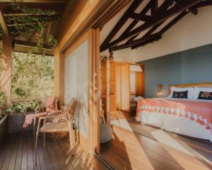a bedroom with a bed and a balcony at Villa Gardena Suites in Praia do Rosa