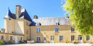 a large brick building with a large roof at Manoir de Pierreville in Audouville-la-Hubert
