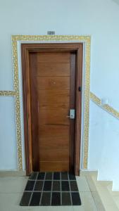 a wooden door in a room with a checkered floor at Eva Apparts "situé à Kotto Baden Baden" - PARKING CAMERA BALCON WIFI CLIM CONFORT in Douala