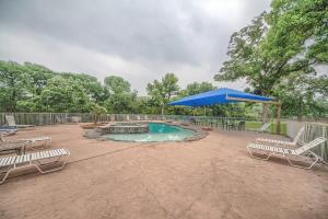 a swimming pool with chairs and a blue umbrella at WW A302 River Relaxation in New Braunfels