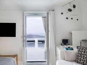 a bedroom with a door leading to a balcony at Cosmopolitan Suites - Small Luxury Hotels of the World in Fira