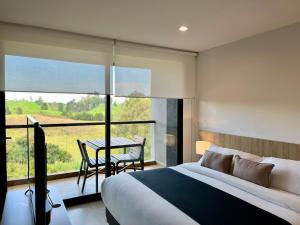 a bedroom with a bed and a balcony with a table at Rioverde Living suites- Apartahotel in Rionegro