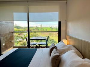 a bedroom with a bed and a large window with a table at Rioverde Living suites- Apartahotel in Rionegro