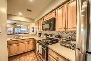 a kitchen with wooden cabinets and a stove top oven at CW C101 Condo de Comal in New Braunfels