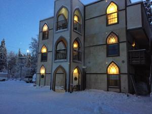 een groot gebouw in de sneeuw met lichten aan bij Abbey Archway Inn in Fairbanks