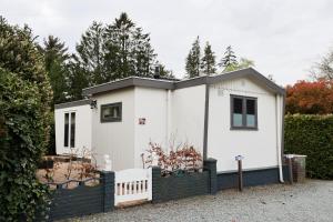 a small white house with a black fence at Knus Relaxchalet met Privé Hottub in Voorthuizen
