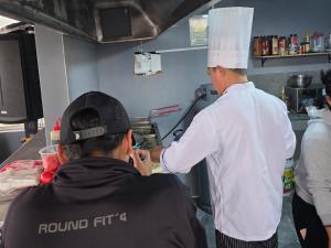 a man in a kitchen with a chef preparing food at Hostal New York in Jauja
