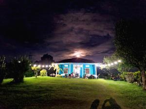 a blue house with lights on a field at night at Hotel Casa de Teja in Norcasia