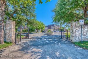 a gate to a driveway with trees and a building at SS B4 Riverside Condo in New Braunfels