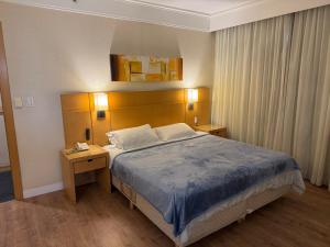 a hotel room with a bed and a night stand with a phone at Flat Executivo em Guarulhos - 6 in Guarulhos