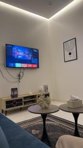 a living room with two tables and a tv on the wall at وحده نجمة الفندقيه2 in Al Qurayyat