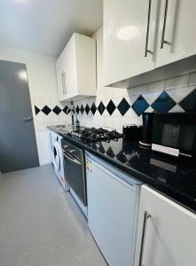 a kitchen with white cabinets and a stove top oven at Cozy 1 bed city apartment in Peterborough