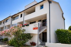 a white apartment building with a balcony and flowers at Apartments Urban Porec in Poreč