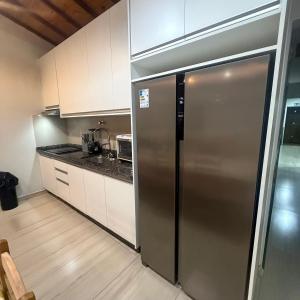 a stainless steel refrigerator in a kitchen with white cabinets at Katie Studio Prime Hotel Extrema MG + breakfast in Extrema