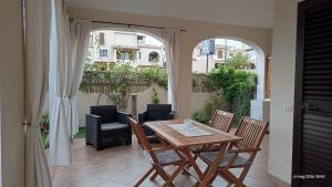 a table and chairs on a patio with an archway at Appartamenti Il Glicine Villasimius in Villasimius
