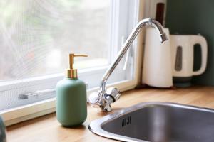 a bottle of soap is sitting next to a sink at Sfeervol Boschalet 5 persoons met Sauna in Voorthuizen