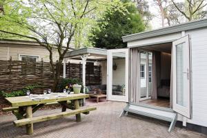 a patio with a picnic table and a pavilion at Sfeervol Boschalet 5 persoons met Sauna in Voorthuizen