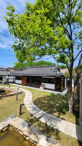 a house with a tree and a walkway at 전주한옥마을 자하연해랑 in Jeonju