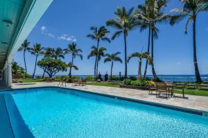 a swimming pool with palm trees and the ocean at Lahaina Shores 320 in Lahaina