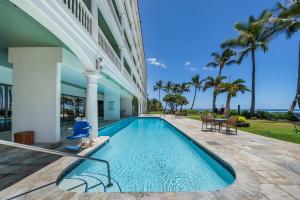 a swimming pool in front of a building with palm trees at Lahaina Shores 320 in Lahaina