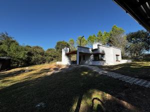 a house on a hill with trees in the background at La Pausa Córdoba, casa en Los Reartes in Los Reartes
