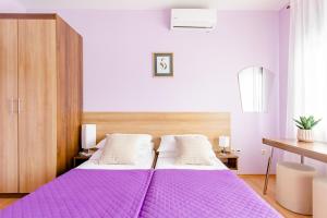 a bedroom with two beds with purple sheets at Apartments Mara near Split Airport in Kastel Stafilic