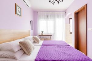 a purple and white bedroom with a large bed at Apartments Mara near Split Airport in Kastel Stafilic