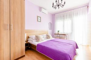 a bedroom with a purple bed and a chandelier at Apartments Mara near Split Airport in Kastel Stafilic