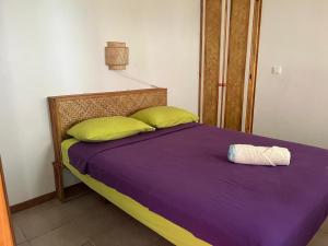 a bed with purple sheets and green pillows in a room at Pension Te Aroha - Te Haumaru in Maatea