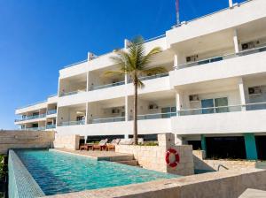 ein Gebäude mit einem Swimmingpool und einer Palme in der Unterkunft The Mint Resort Isla Mujeres in Isla Mujeres