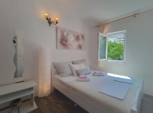 a white room with a bed and a window at Apartments Vuleta in Pag