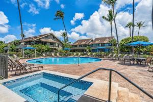 a swimming pool with chairs and umbrellas at a resort at Kahana Village 4 in Lahaina
