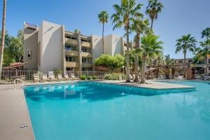a large swimming pool with palm trees in front of a building at Relaxing Condo with Parking - Minutes to Old Town! in Scottsdale