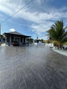 a parking lot in front of a house with a palm tree at RusanHome Pengkalan Chepa in Pengkalan Cepa