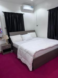 a bedroom with a large bed with white sheets at New Luxury in Gwarinpa