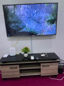 a desk with a large television on a wall at New Luxury in Gwarinpa