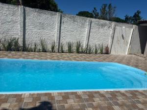 a blue swimming pool in front of a fence at pousada Bela Rosa in Santa Cruz Cabrália