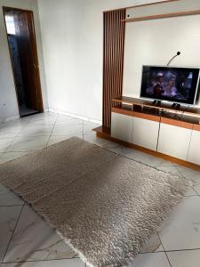 a living room with a television and a rug at Casa do kell in Itaúnas