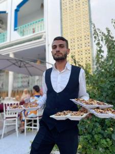 a man is holding three plates of food at Morjana Castle in Sousse