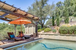 a swimming pool with two chairs and an umbrella at Leslie Creek House in Mark West Springs