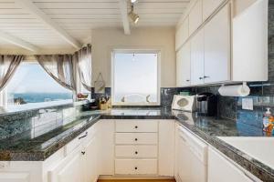 a kitchen with white cabinets and a large window at Sunset Escape in Bodega Bay