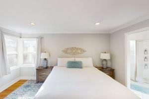 a white bedroom with a large bed and two windows at James House in Santa Rosa