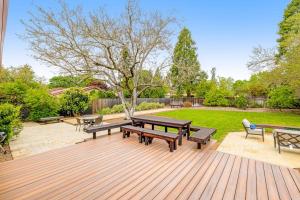 a wooden deck with picnic tables and benches on it at Kenwood Retreat in Kenwood +22 photos