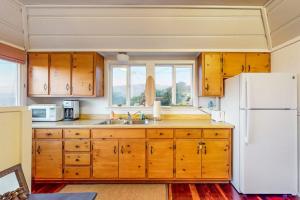 a kitchen with wooden cabinets and a white refrigerator at Seaside Cottage in Bodega Bay