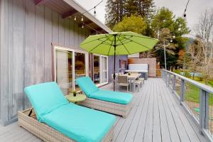 a patio with chairs and an umbrella on a deck at Riverfront Escape in Monte Rio