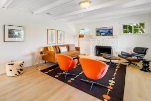 a living room with orange chairs and a fireplace at Bird and Barrel Vineyard Farmhouse in Healdsburg +28 photos