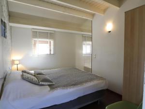 a white bedroom with a bed and a mirror at Le Chemin des Framboises in Malmedy
