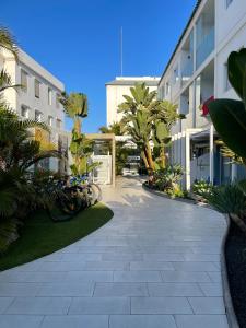 a walkway in front of a building with palm trees at 51 E-scape Home in Corralejo