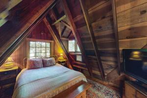 a bedroom with a bed and a tv and wooden walls at Dreamcatcher Cottage in Cazadero