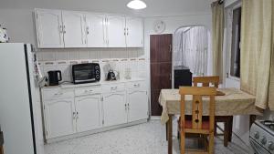 a kitchen with white cabinets and a table and a microwave at Zona Sur, Bajo Seguencoma Flat in La Paz